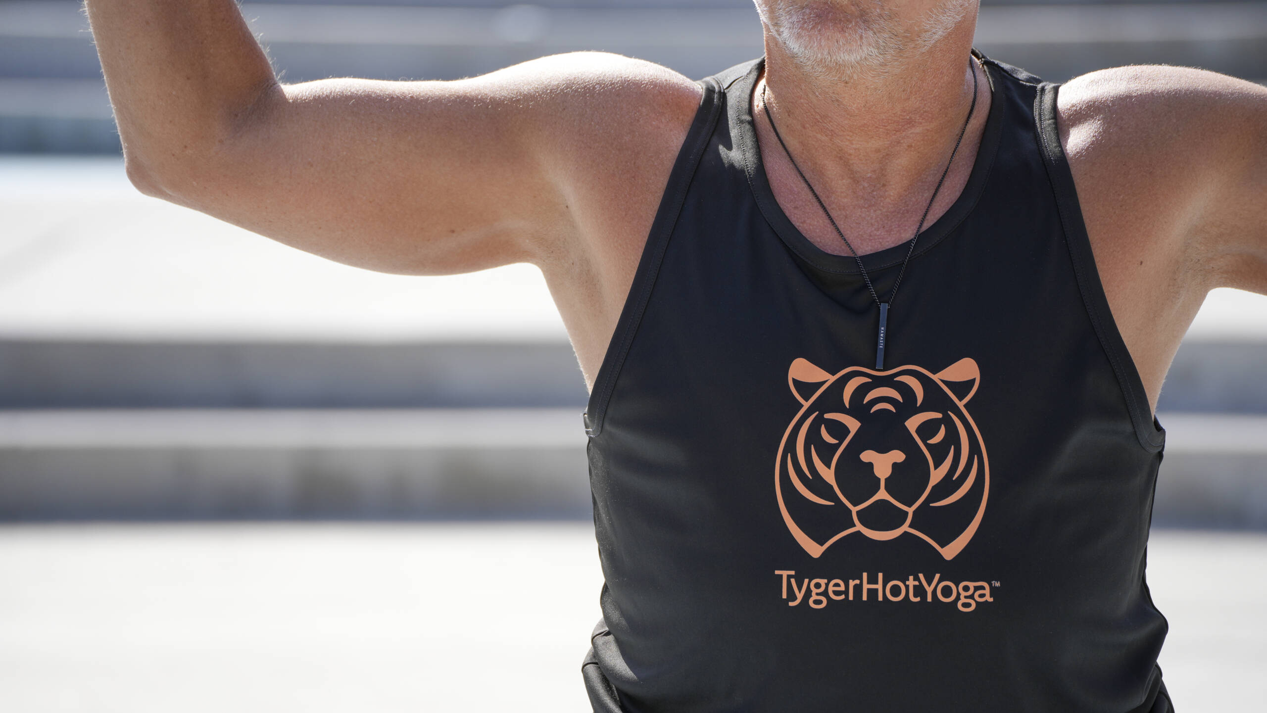 A man doing yoga wearing a Tyger Hot Yoga tanktop.